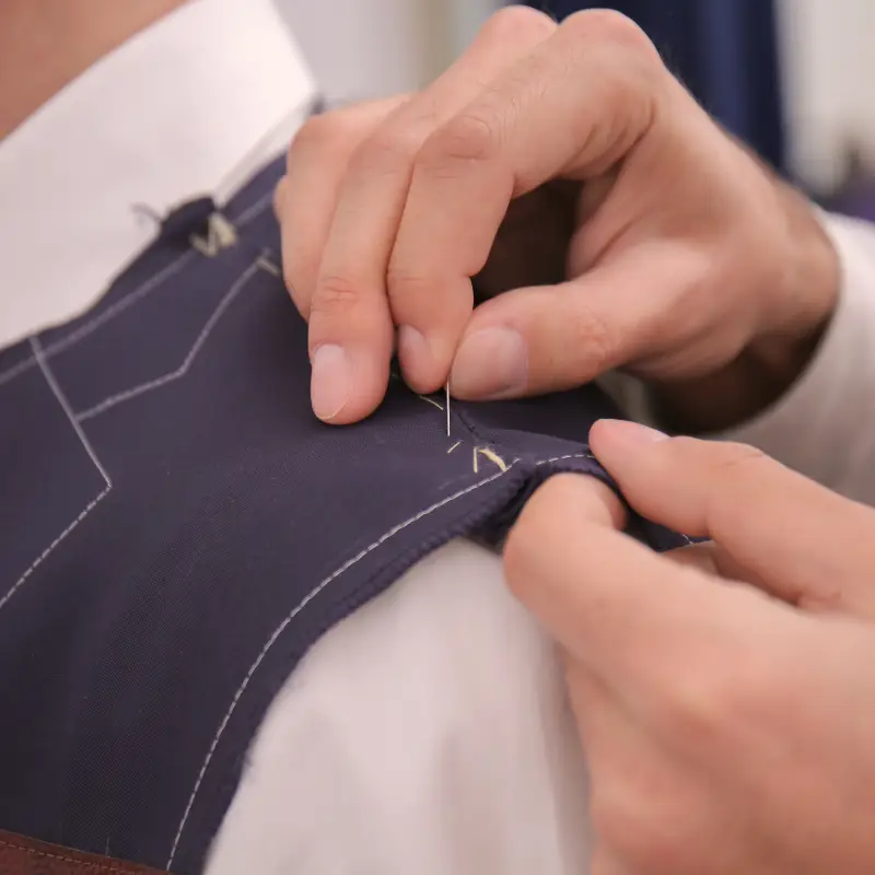 Tailor hand-stitching a seam on a navy suit vest